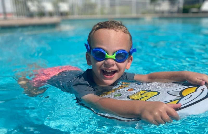 Young swimmer kicking across the pool holding a kickboard