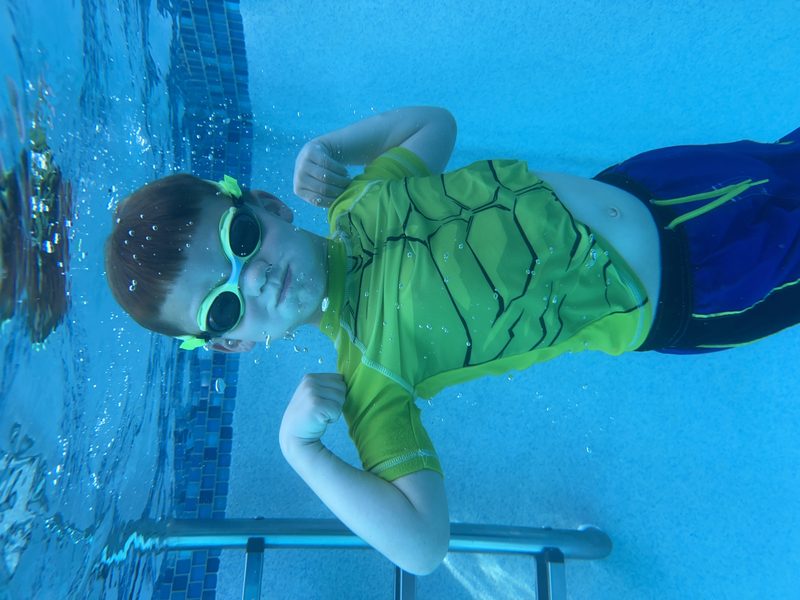 Child swimming underwater in goggles