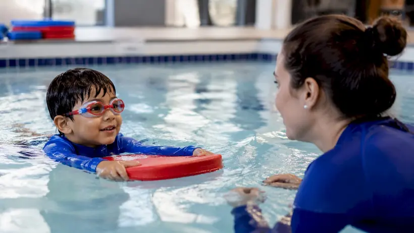 Swim instructor teaching young boy in pool