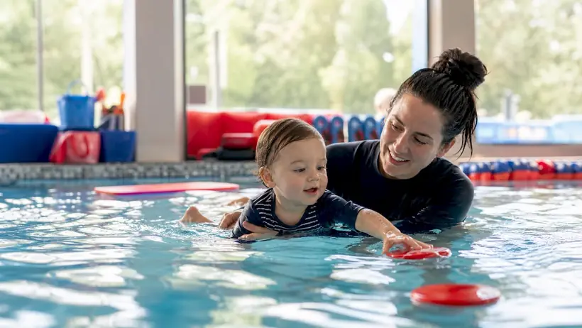 Instructor supporting toddler in swim lesson