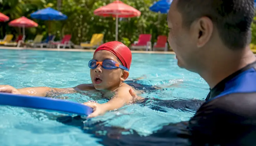 Young child practicing swim kicks with instructor support