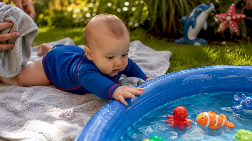 Infant reaching toward floating swim toys in pool
