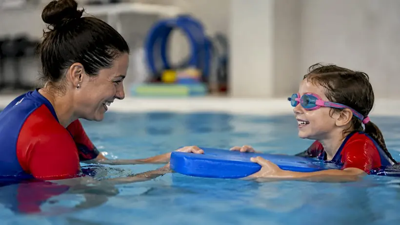 Close-up child practicing freestyle swim with instructor