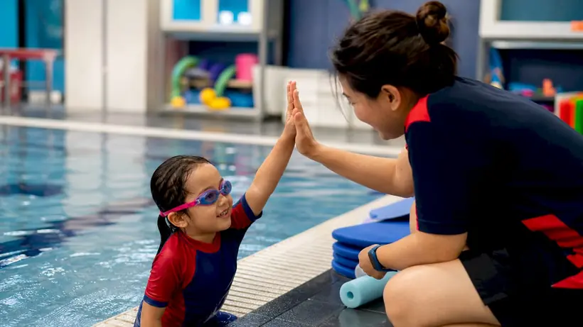 Swim instructor teaching child in pool