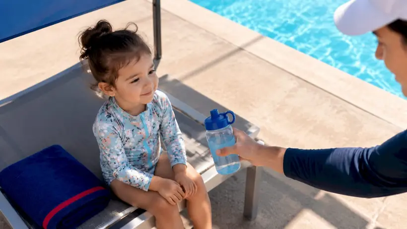 Toddler cooling off beside shaded pool