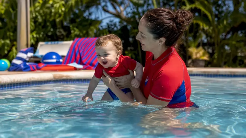 Instructor holding infant safely in pool water