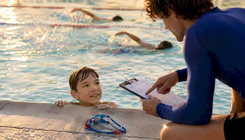 Swim instructor pointing at progress note clipboard