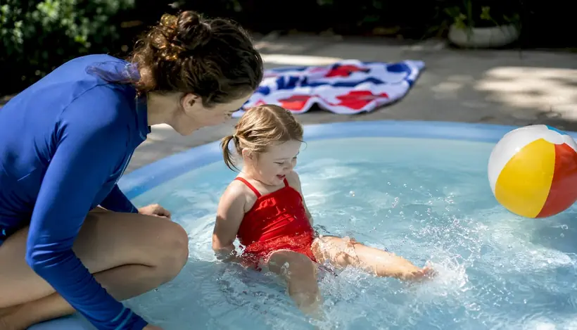 Parent holding toddler’s hands blowing bubbles