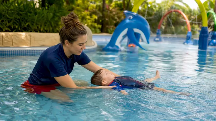Swim instructor supporting toddler in pool