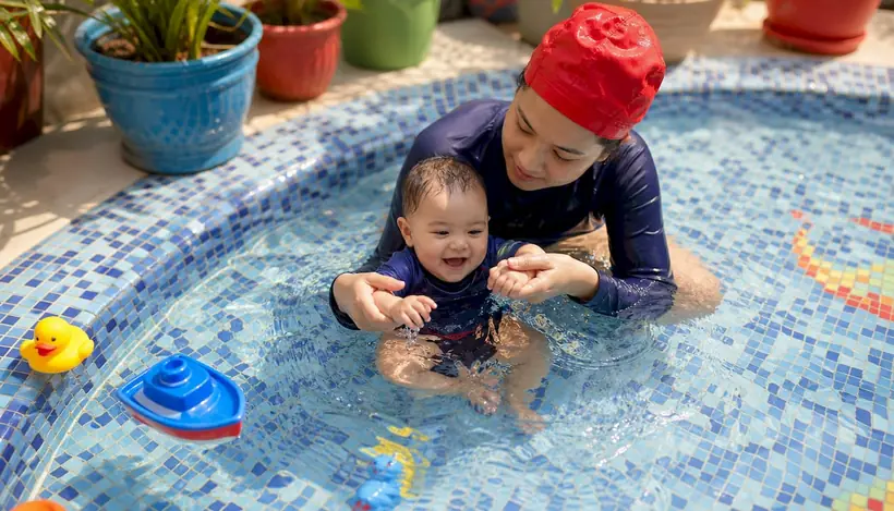 Mother guiding infant in swim lesson pool