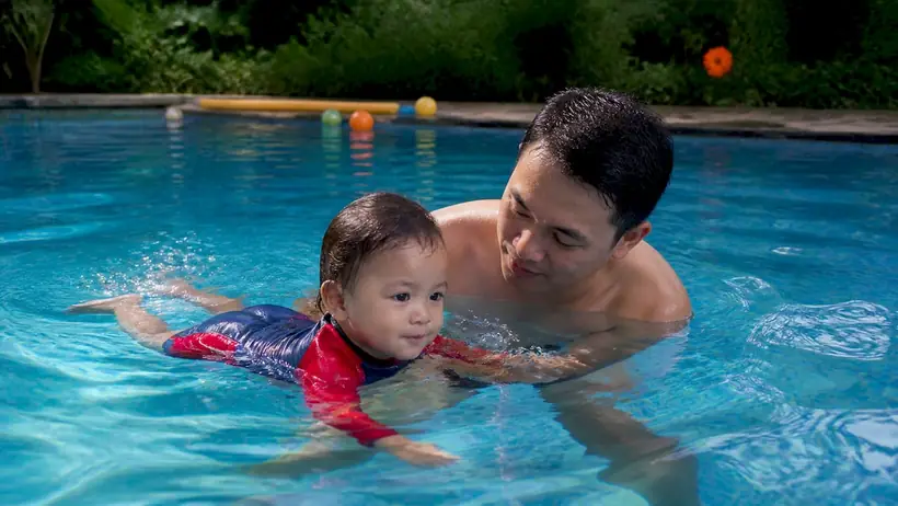 Parent supporting toddler during private swim lesson