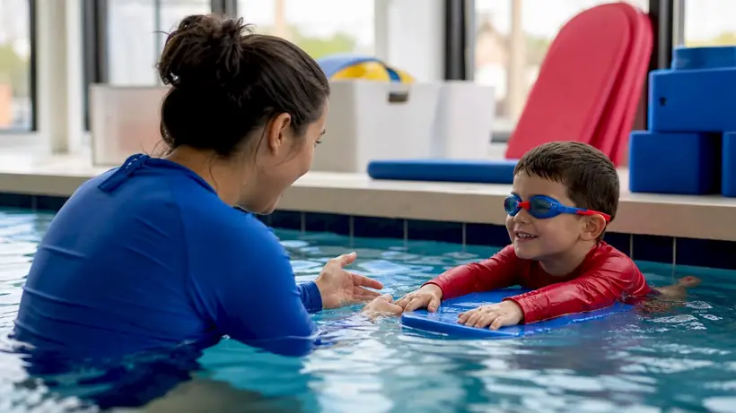 Toddler supported by swim coach in pool