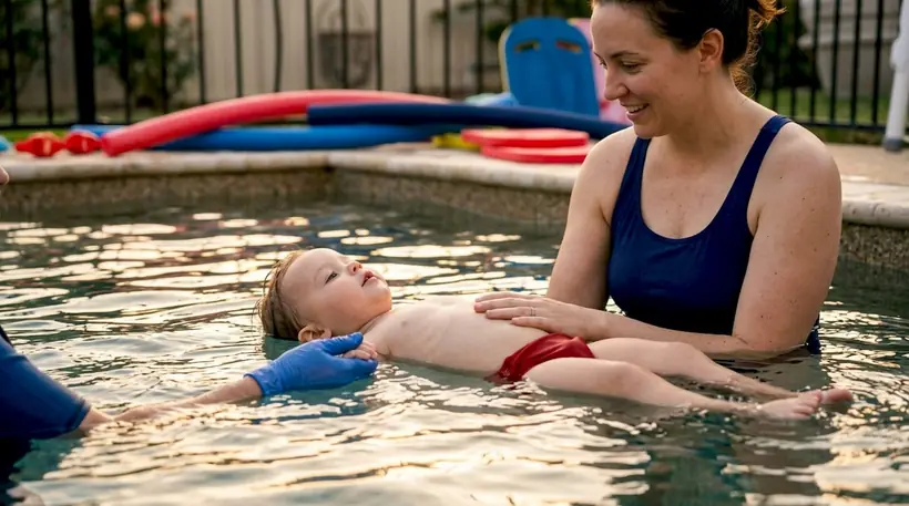 Parent cradling toddler during shallow water swim lesson