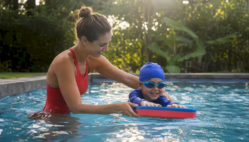Instructor guiding child swim technique in pool