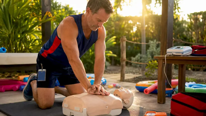 Swim instructor performing CPR on training manikin