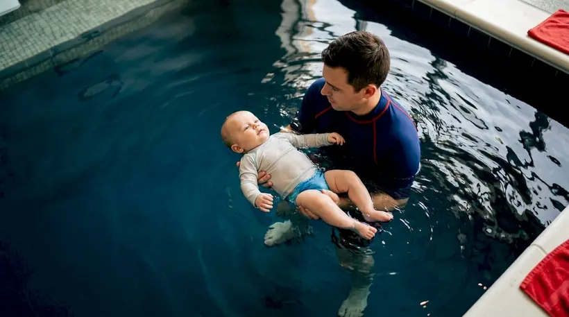 Instructor supporting infant in warm pool