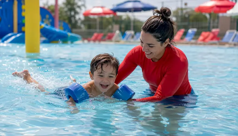 Swim instructor supporting toddler in pool