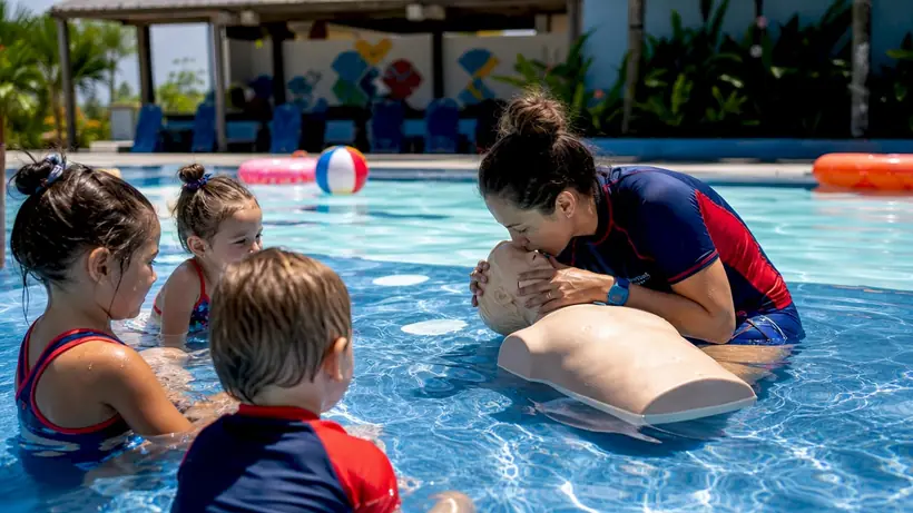 Swim instructor demonstrating CPR to children in pool