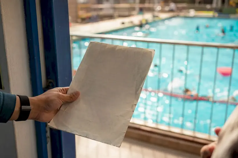Instructor holding insurance certificate near pool